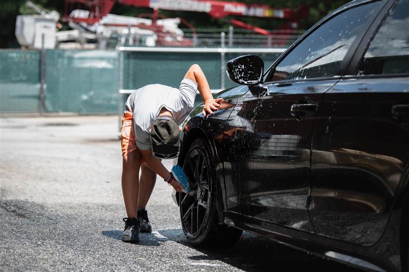 Alloy wheels being cleaned by hand on a black car